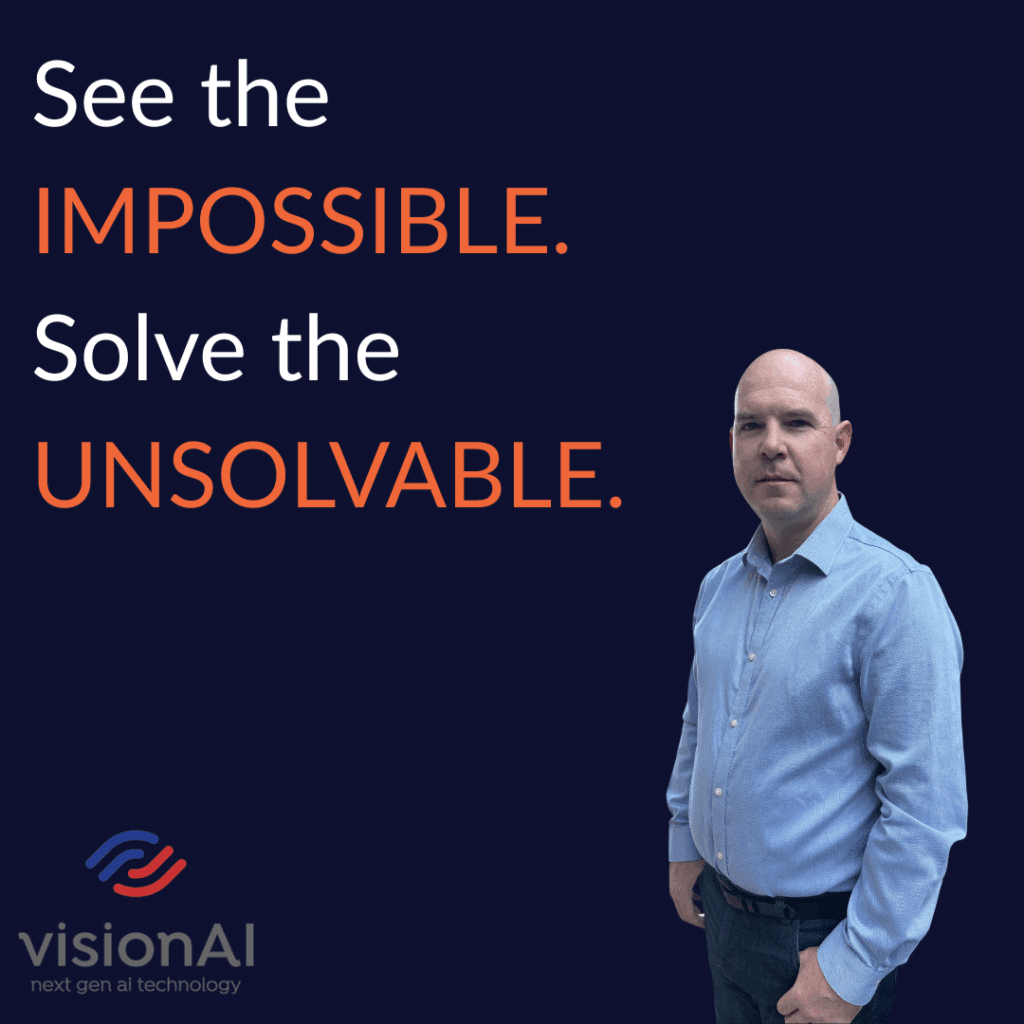 Man in a blue shirt standing beside bold text that reads “See the IMPOSSIBLE. Solve the UNSOLVABLE.” with the visionAI logo below.